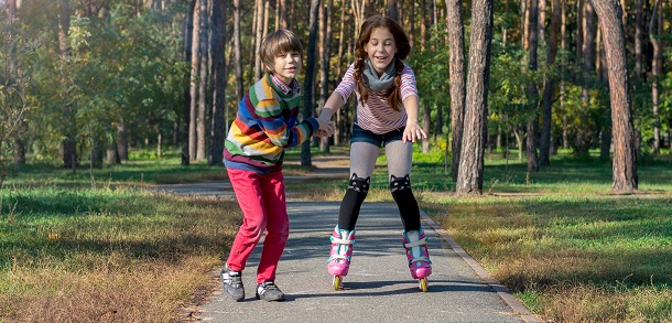 boy supporting girl who is learning to rollerskate